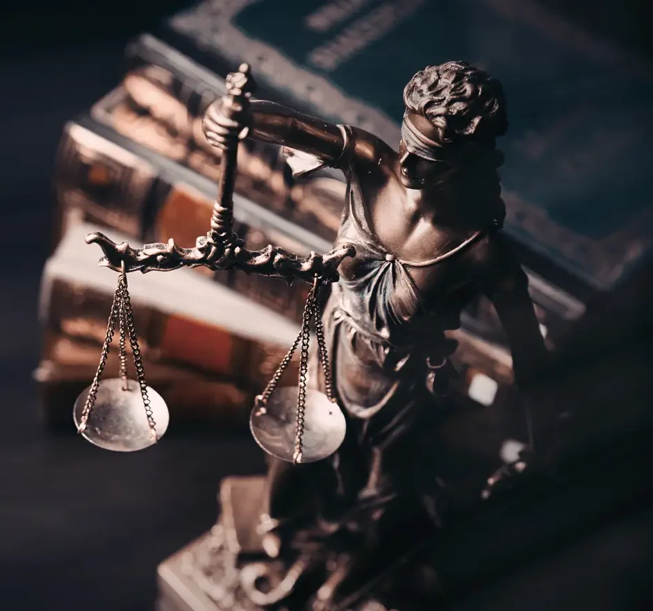 Aerial shot of statue of Lady Justice on desk with books.