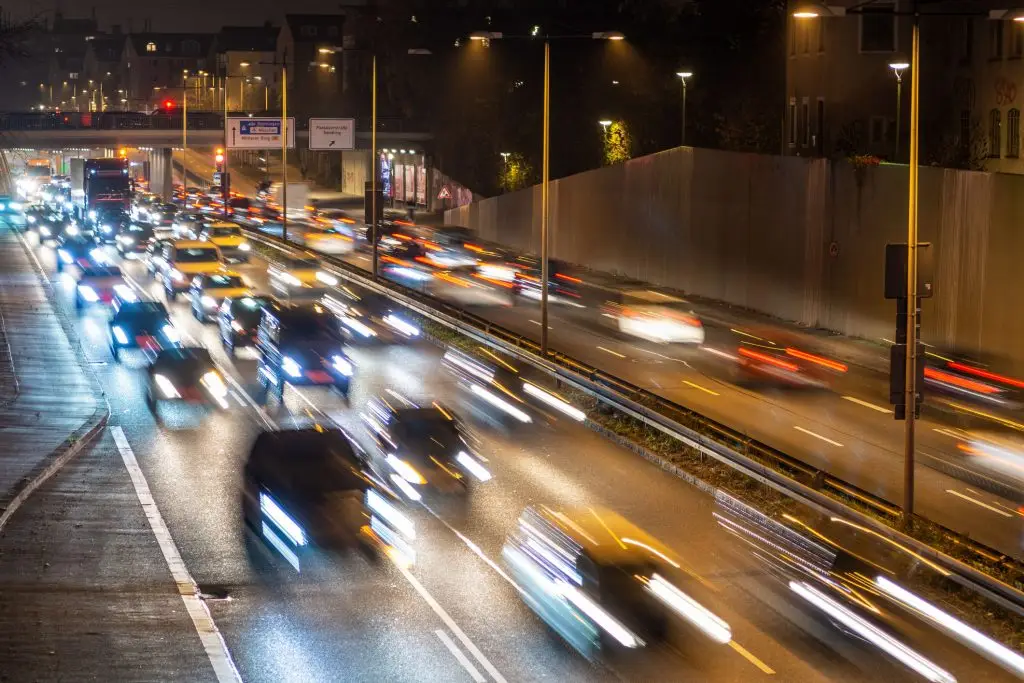 Speeding traffic moves quickly along a city highway in Munich, Germany. Slow shutter speed and long exposure photography produce light streaks.