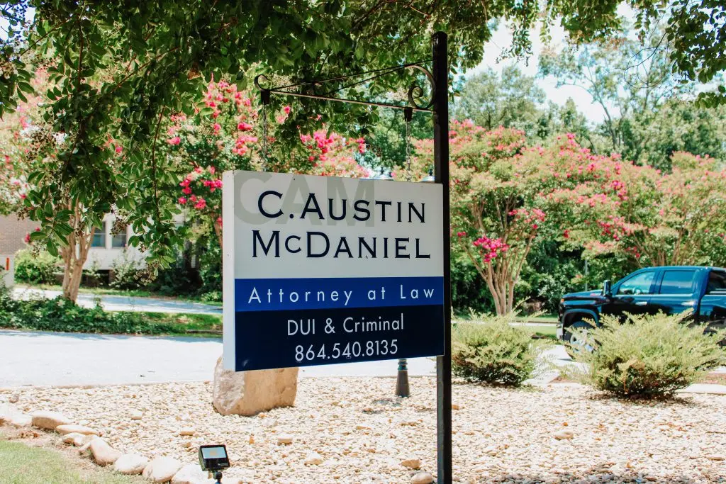 Sign outside of Austin McDaniel Law office that reads "C. Austin McDaniel Attorney at Law DUI & Criminal 864.540.8135" on a bright sunny day.