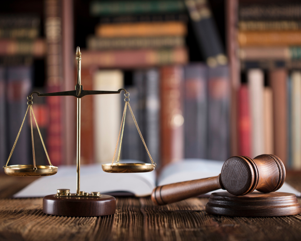 Close up shot of lawyer's desk with scales of justice, gavel, and legal documents.