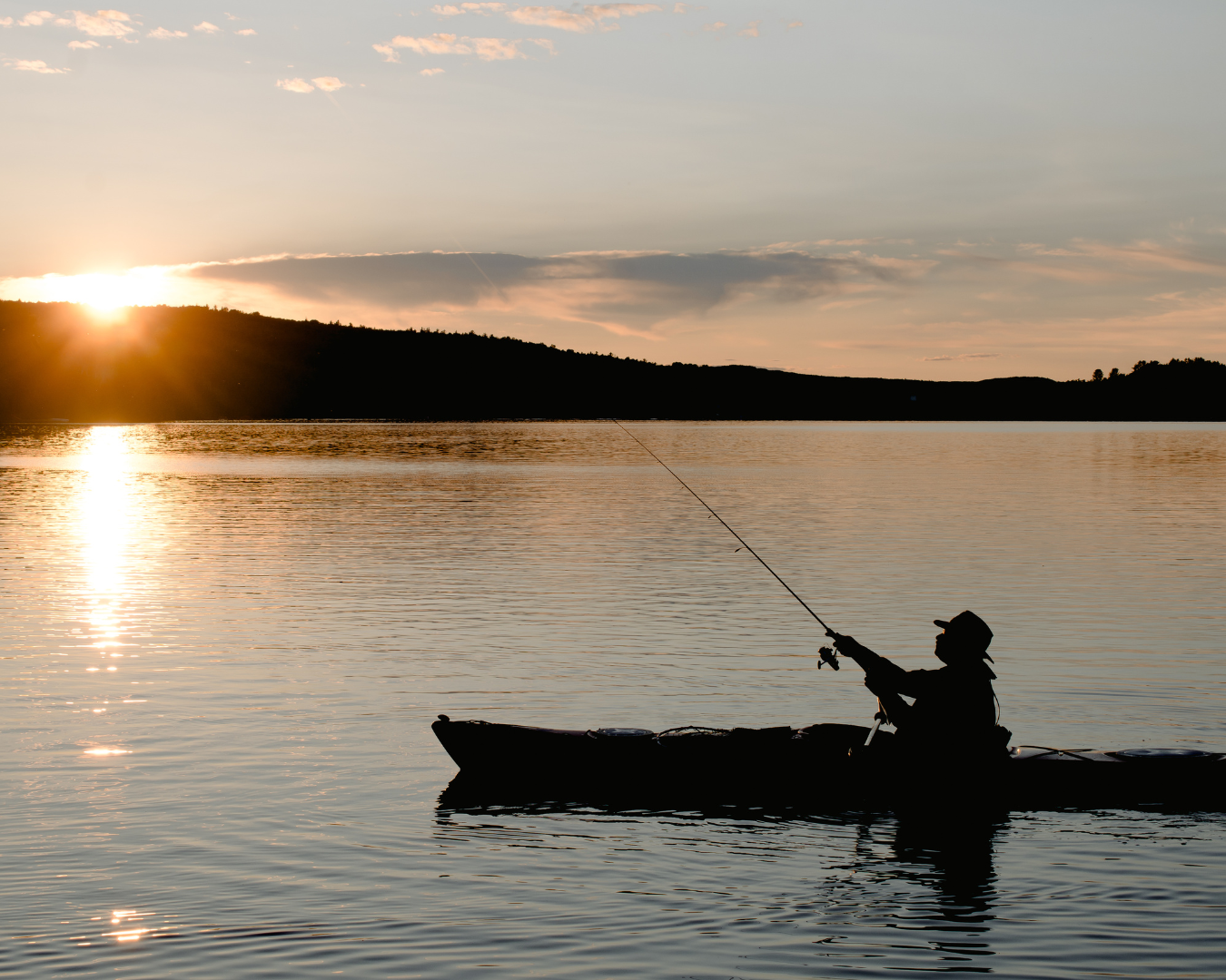 Beautiful sunset shot of fisherman fishing in kayak at sunset.